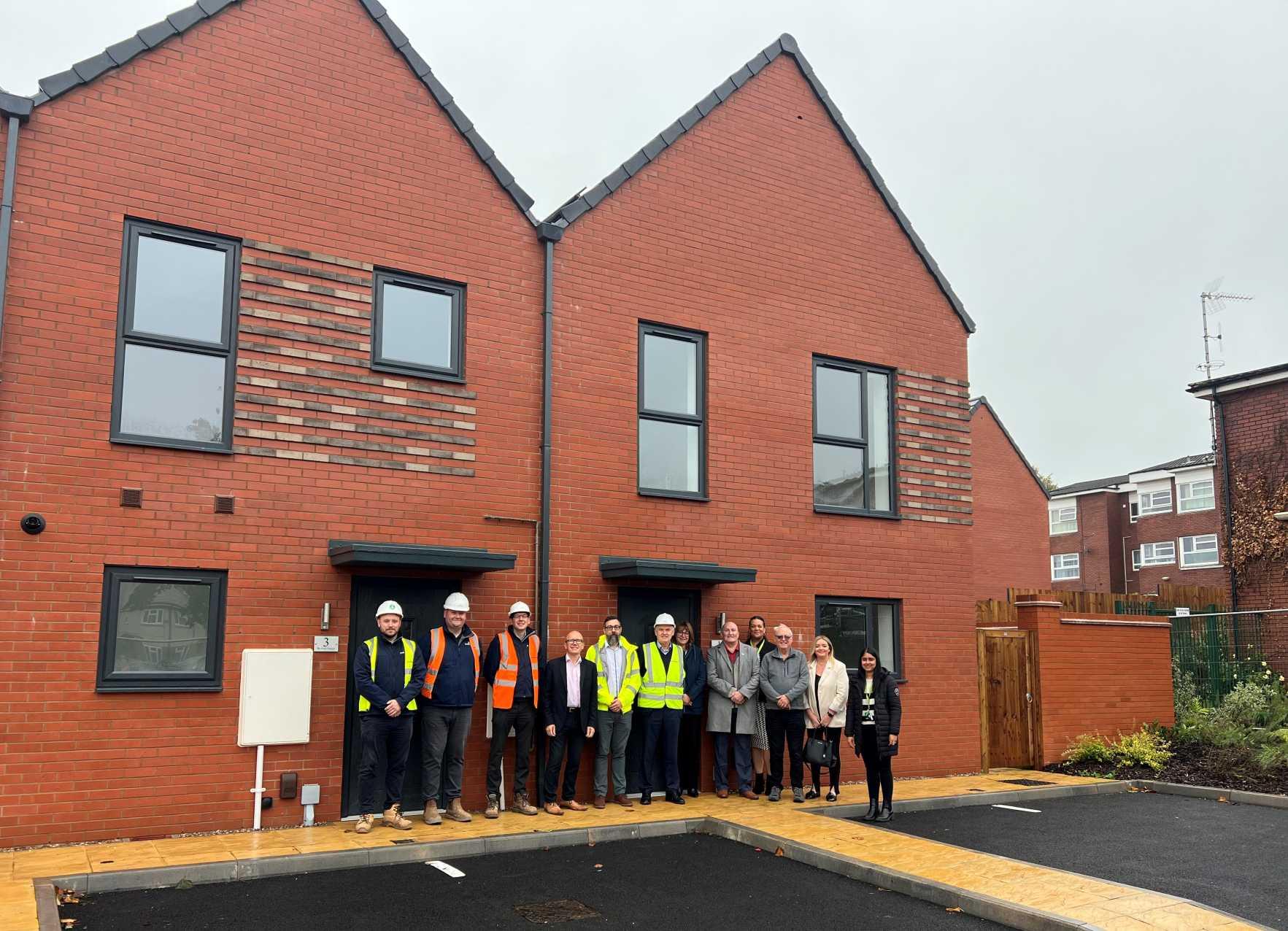 group of representatives standing outside of the finished homes.